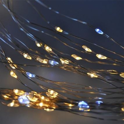 Svetielkujúce drôtiky s LED diódami vyžarujúce teplé biele a chladné biele svetlo. Drôtiky sú tenké a prepletené, vytvárajúce svetelný efekt. Tmavé pozadie zvýrazňuje osvetlenie.