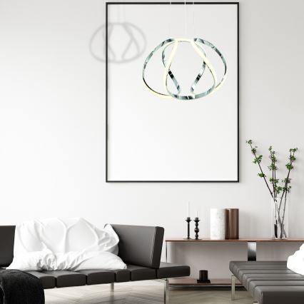 Závesné svietidlo svieti. Je z chrómovanej ocele, pozostáva z prepletených kruhov s LED osvetlením. Svietidlo je zavesené zo stropu na kábloch.