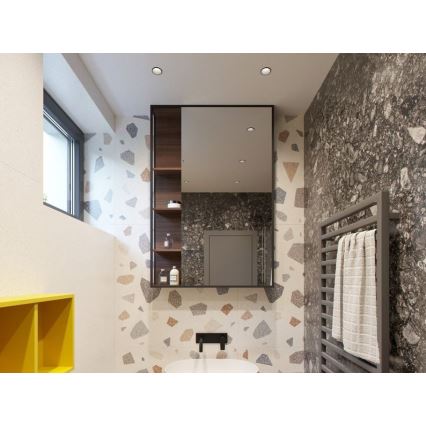 Zrkadlo s poličkami odráža kúpeľňu s dlažbou z mramoru a farebnými kamienkami. Kúpeľňa obsahuje žltú skrinku, radiátor s uterákom a umývadlo.