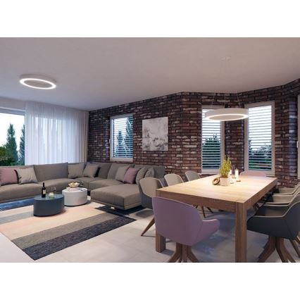 Rohový gauč v obývacej izbe s jedálenským stolom a stoličkami. Steny sú z červených tehál, okná majú žalúzie. Svietidlá sú kruhové, jedno stropné, druhé visiace nad stolom.