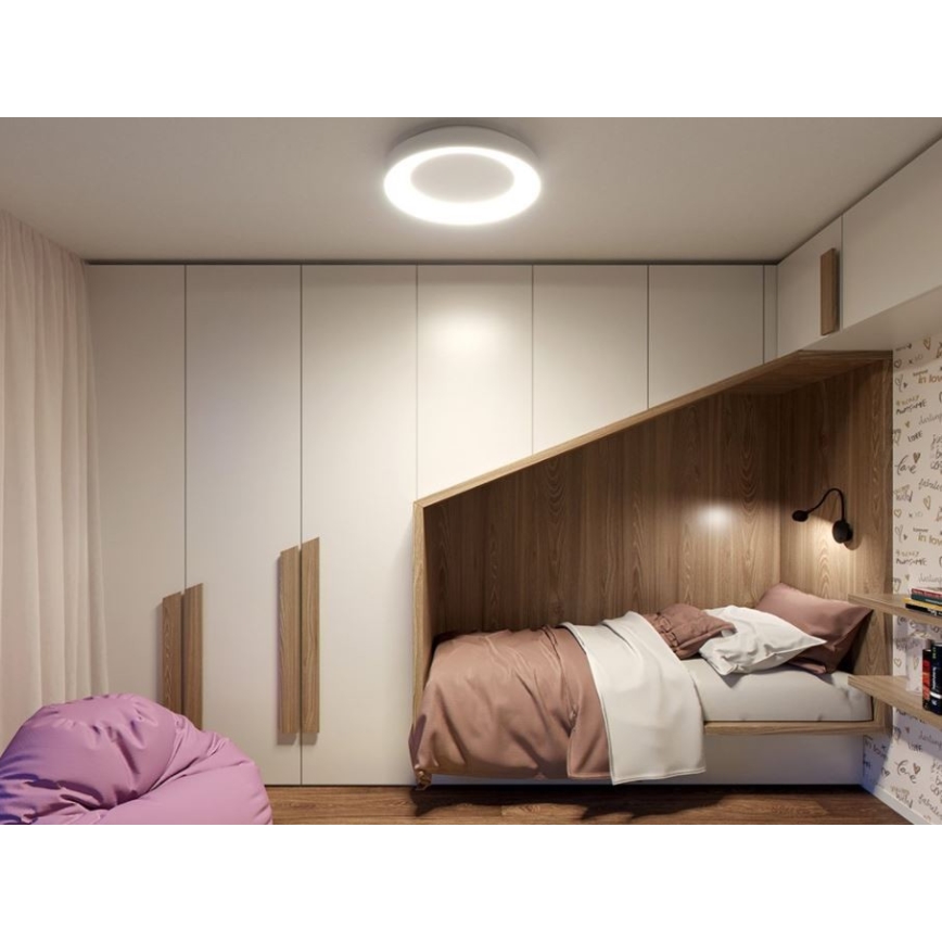 Кругоvá stropná lampa svieti v detskej izbe. Posteľ je zabudovaná do drevenej konštrukcie v blízkosti skrine. V izbe sa nachádza aj fialové kreslo.