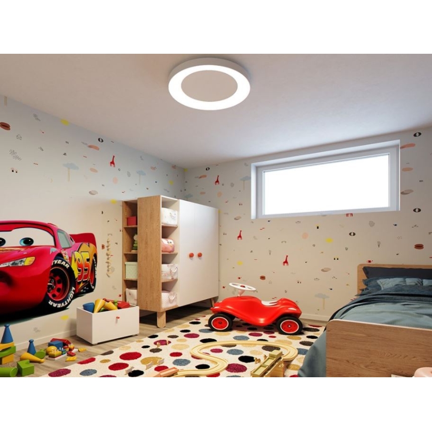 Okrúhle stropné svetlo svieti v detskej izbe. Izba má nábytok z masívneho dreva, hračky a steny sú ozdobené detskými motívmi.