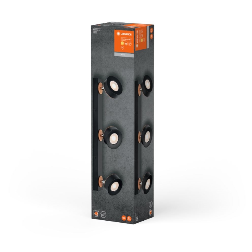 Balenie s nástenným svietidlom: Čierny, štvorbodový reflektor s medenými detailmi je zobrazený na obale. Svietidlo je umiestnené na vertikálne orientovanej krabici.