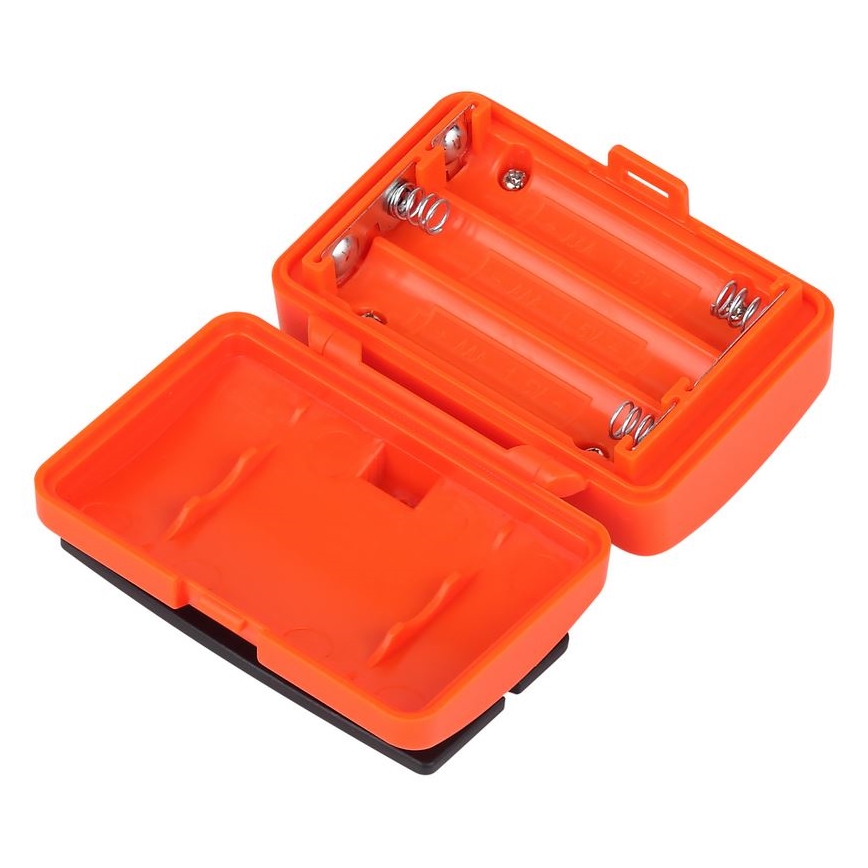 Oranžový plastový držiak batérií je otvorený, ukazuje tri vložené batérie AAA. Je položený na bielom pozadí.