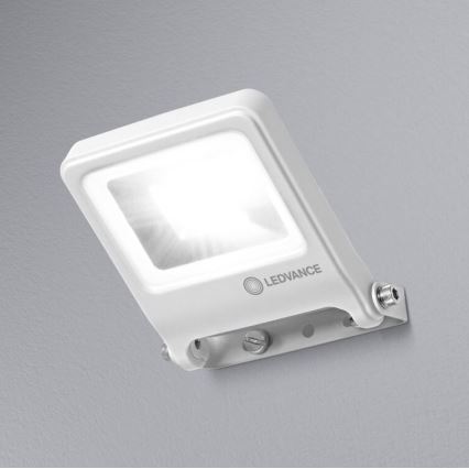 Biela LED lampa svieti. Je pripevnená na stene pomocou kovového držiaka. Na lampe je logo LEDVANCE.