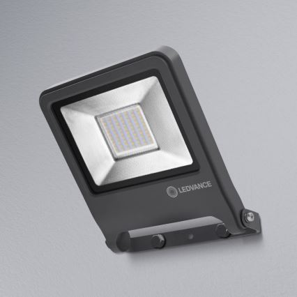 LED reflektor LEDVANCE je pripevnený na stenu. Svieti. Je sivý.