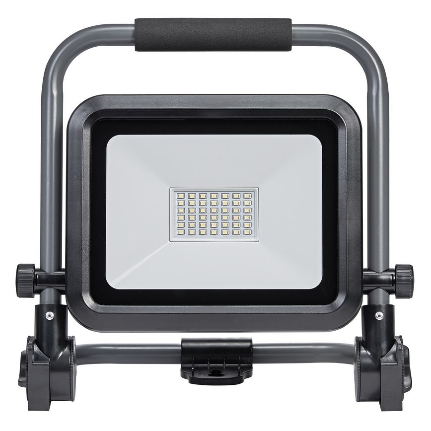 LED pracovné svetlo s rúčkou a nastaviteľným stojanom svieti. Svetlo je umiestnené na čiernom a sivom kovovom ráme.