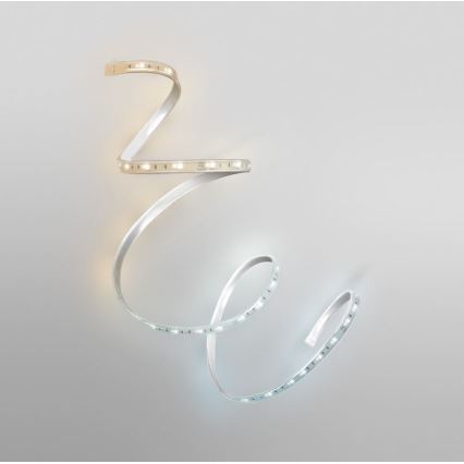 LED pásik je stočený pred svetlosivým pozadím. Pásik vyžaruje teplé a studené biele svetlo. Na jednom segmente je viditeľný text: „24V DC 12W/m 120 LED/m“.
