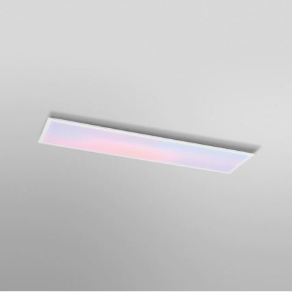 Dlhý obdĺžnikový LED panel svieti jemnými pastelovými farbami, je pripevnený k stropu svetlosivej farby.