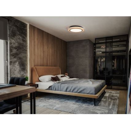 Moderná spálňa s posteľou a šedou prikrývkou, v ktorej je umiestnené stropné svietidlo kruhového tvaru. Vedľa postele sa nachádza vstavaná sklenená skriňa a pracovný stôl. Steny sú z dreva a betónu.