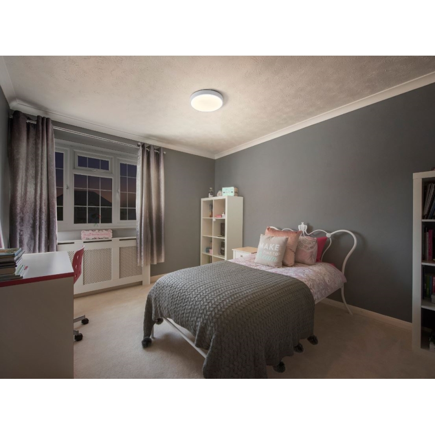 Svietidlo svieti v detskej izbe. Izba obsahuje posteľ s šedou prikrývkou, písací stôl a knihovňu. Steny sú tmavosivé.