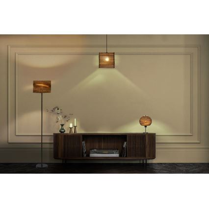 Tri stojacie lampy s hnedými tienidlami z prírodného materiálu sú umiestnené v interiéri pred hnedým dreveným nábytkom. Jedna lampa je stojaca na podlahe, druhá na komode a tretia visí zo stropu. V pozadí je béžová stena s lištami.