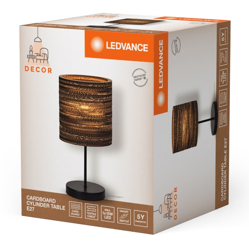 Stolová lampa z kartónu s čiernym podstavcom je zobrazená na obale. Obal je biely s oranžovými prvkami a značkou LEDVANCE. Text na obale: „CARDBOARD CYLINDER TABLE E27“.