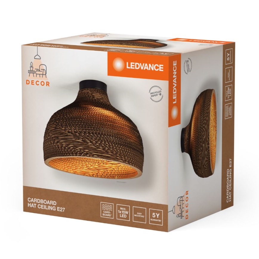 Kartónová stropná lampa svieti. Balenie zobrazuje lampu z lepenky, svietiacu teplým svetlom. Na obale je názov LEDVANCE a text „CARDBOARD HAT CEILING E27“.