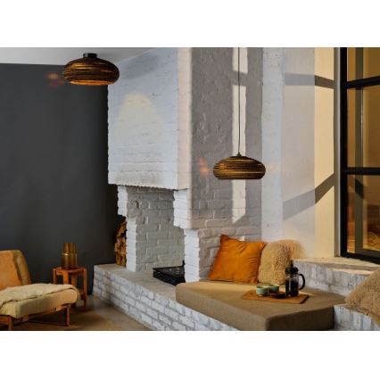 Dve okrúhle závesné lampy s hnedým vrúbkovaným tienidlom svietia v interiéri. Lampy visia nad sedačkou pri bielom tehlovom krbe a oknom.