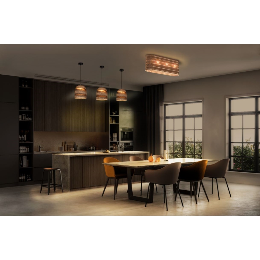 Trojica závesných lámp a stropné svietidlo svietia v modernej jedálni s kuchyňou. Svietidlá sú hnedé, pletené. Jedálenský stôl je obklopený stoličkami.