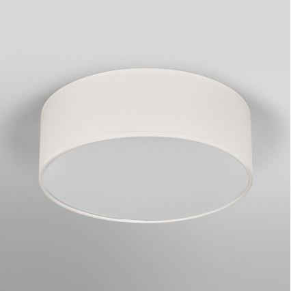 Biela stropná lampa s valcovým tienidlom je pripevnená na svetlom sivom strope. Lampa je osvetľovacím telesom.