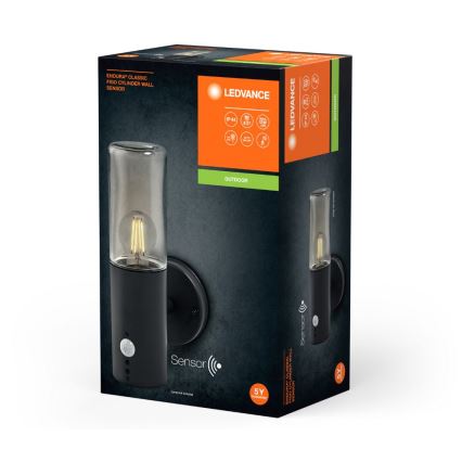 Čierna nástenná lampa s pohybovým senzorom a skleneným tienidlom je zobrazená v balení. Balenie uvádza názov výrobcu LEDVANCE a označenie IP44, označenie Outdoor a záruku na 5 rokov.