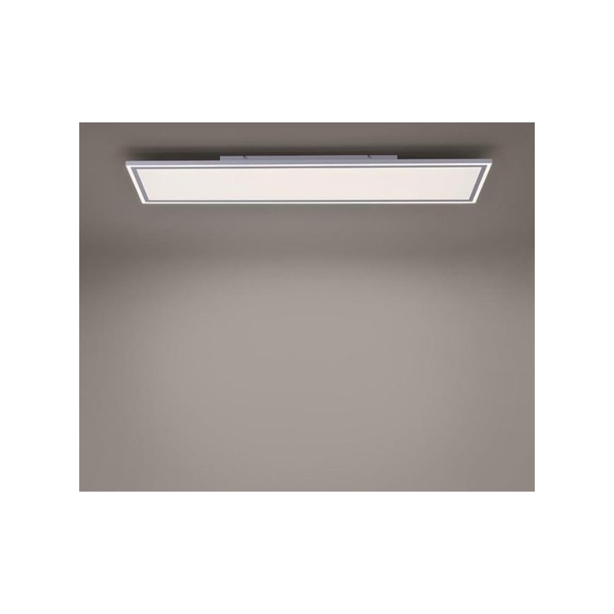 Dlhý obdĺžnikový LED panel je pripevnený k stropu. Svieti v neutrálnej miestnosti so sivými stenami.