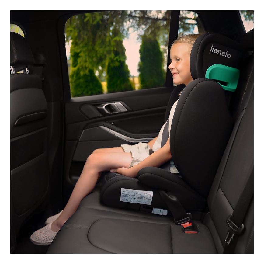 Dievča sedí v čiernej autosedačke Lionelo v zadnej časti tmavého auta. Pozera sa smerom k oknu, za ktorým je vidieť zeleň.