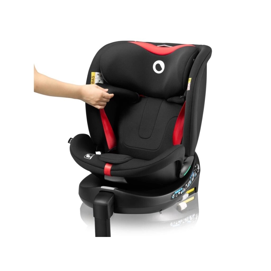 Čierna autosedačka s červenými detailmi, ktorú nastavuje ruka. Sedačka je otočná, s opierkou hlavy a bezpečnostnými pásmi. Je umiestnená na bielom pozadí.