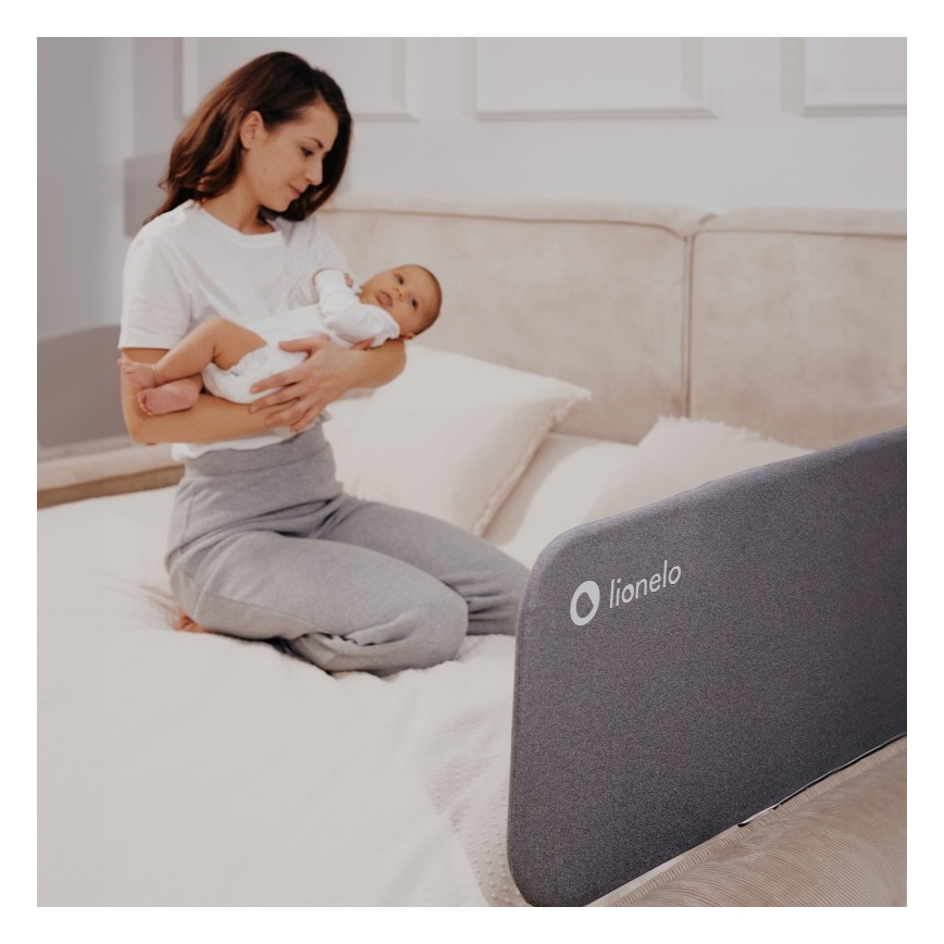 Žena drží dojča na posteli. Pri posteli je sivá zábrana s logom lionelo.