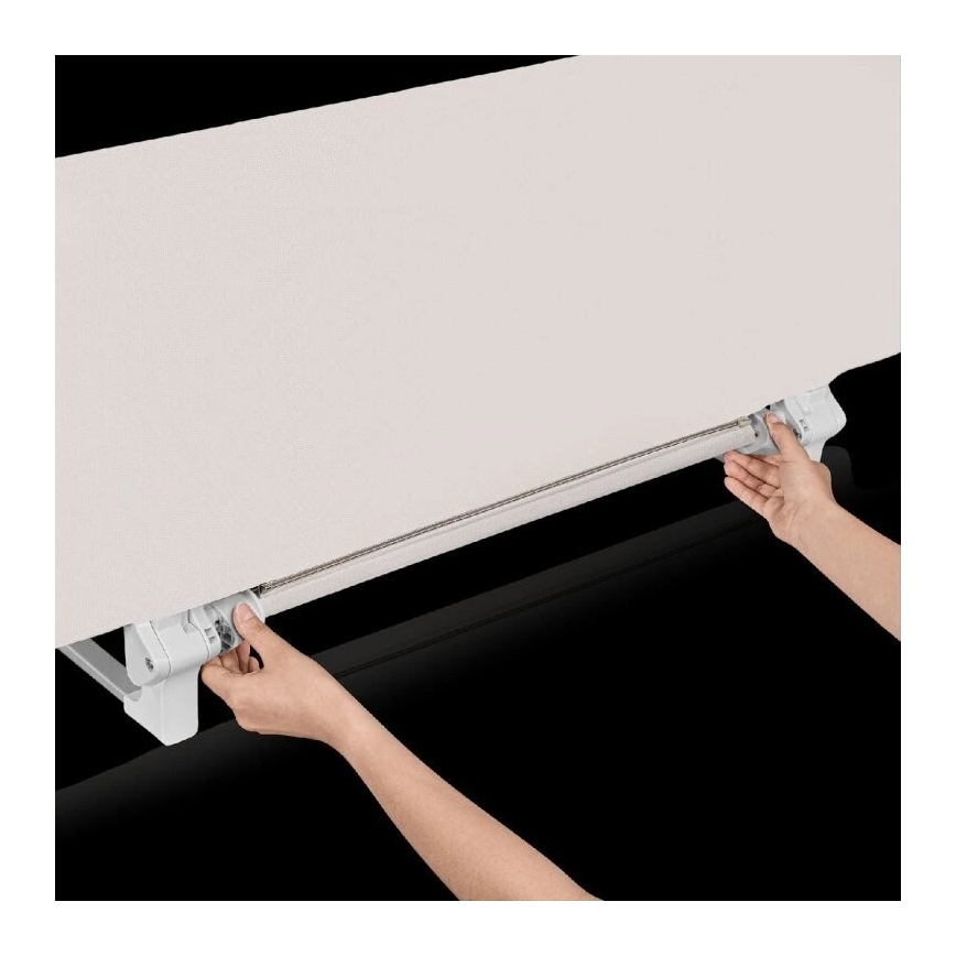 Dve ruky ovládajú mechanizmus rolety. Svetlo béžová látka rolety sa pohybuje po koľajničke. Koľajnička je pripevnená k bielemu držiaku.