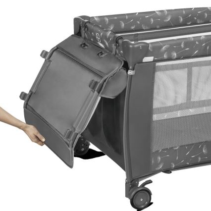 Prebaľovací pult skladacieho cestovného postieľky sa pripája k bočnej stene. Postieľka je sivá s obrázkom púpavy. Postieľka má kolieska.