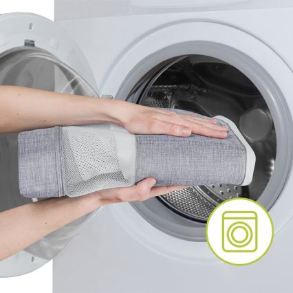 Sivý textilný výrobok v sieťovanom obale vkladajú do práčky. Práčka je biela, s otvorenými dvierkami. Symból prania je znázornený vedľa práčky.