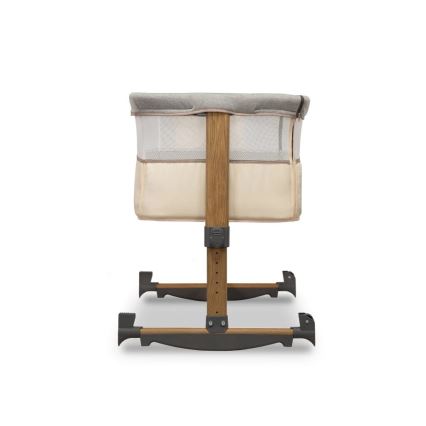 Detská postieľka stojí na drevených nohách s plastovými spojkami. Je vyrobená z dreva a látky, s bočnicami z priedušnej sieťoviny. Postieľka je umiestnená na bielom pozadí.