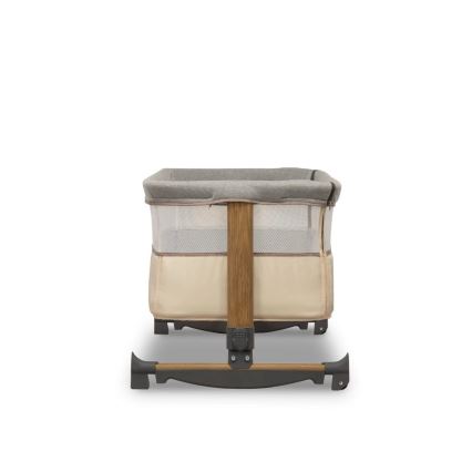 Detská postieľka stojí na drevenom ráme s textilnými bočnicami, čiastočne sieťovanými pre cirkuláciu vzduchu. Postieľka je béžovo-sivej farby.