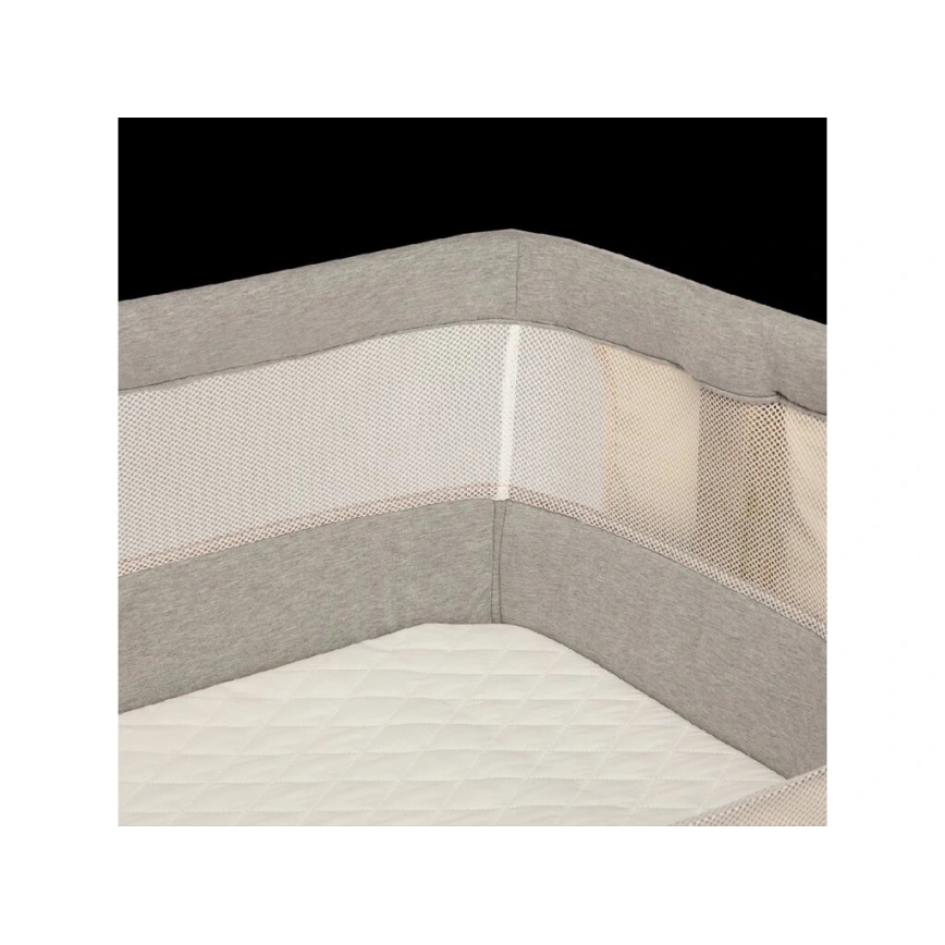 Postieľka s ochrannou mantinelovou vložkou sivých a bielych odtieňov s priedušnou sieťovinou. Vložka je položená na matraci.