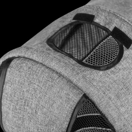 Šedá látková prepravka pre zvieratá má sieťované vetracie otvory. Je zobrazená časť vrchnej časti prepravky na tmavom pozadí.