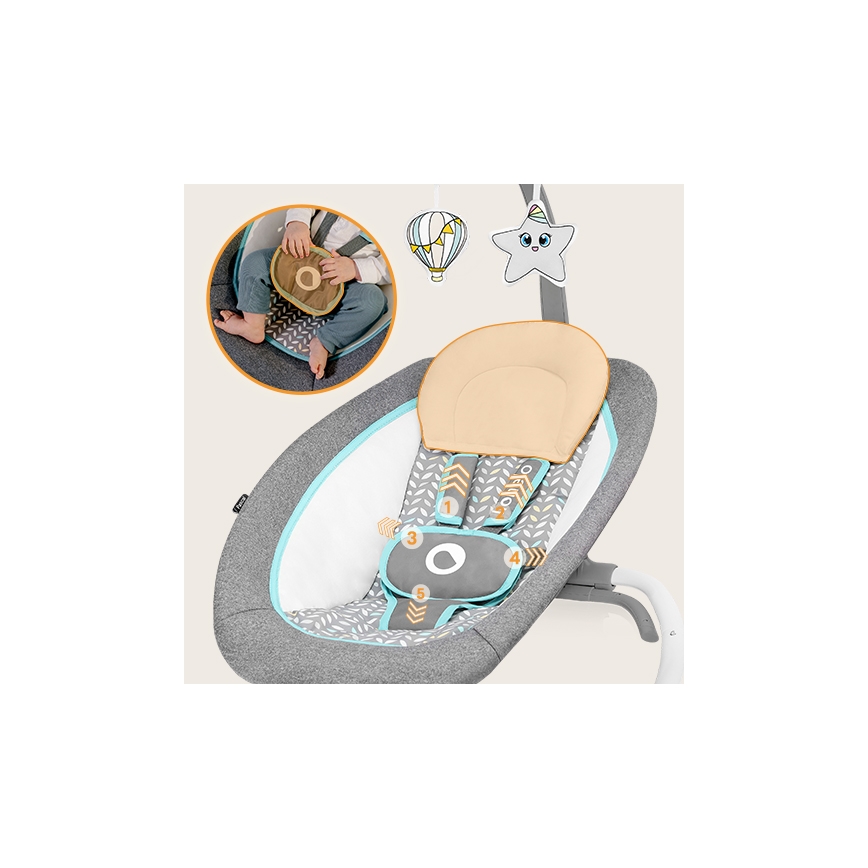 Detská hojdačka s bezpečnostnými pásmi a mäkkým vankúšikom na hlavičku. Dieťa sedí v hojdačke. Hojdačka má ozdobné prvky v tvare balóna a hviezdy.