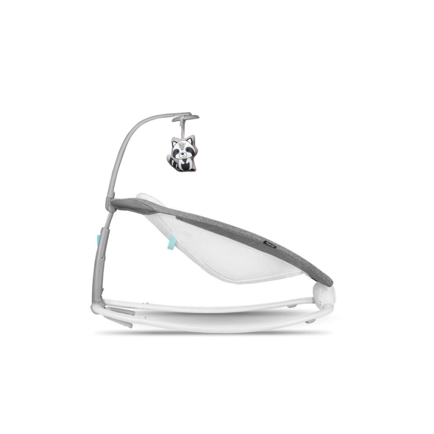 Detská hojdačka s šedým čalúnením sa kýve na bielom podstavci. Nad ňou je oblúk s plyšovou hračkou v tvare mývala.