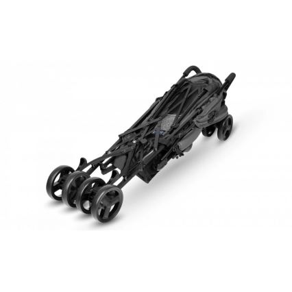 Detský kočík je zložený, stojí na štyroch kolieskach na bielom pozadí. Konštrukcia je tmavá, skladacia.