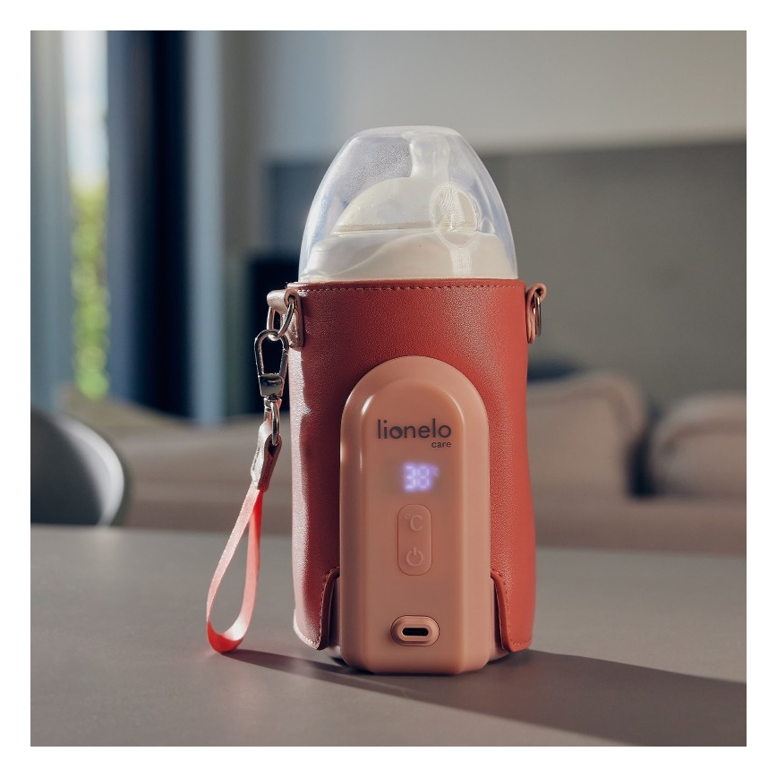 Ohrievač fľašiek s integrovanou fľašou udržiava teplotu 38°C. Zariadenie má ovládacie tlačidlá, displej a popruh. Nachádza sa na stole v obytnom priestore. Značka: Lionelo care.