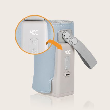 Prehrievač fľaštičiek s displejom ukazuje 40 °C. Má pútko a je zabalený v bledomodrom puzdre. Na spodku je viditeľný USB-C konektor.