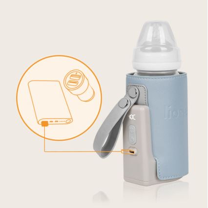 Prehrievač detskej fľaše v modrom puzdre sa nabíja pomocou externého akumulátora. Súčasťou je popruh na prenášanie.