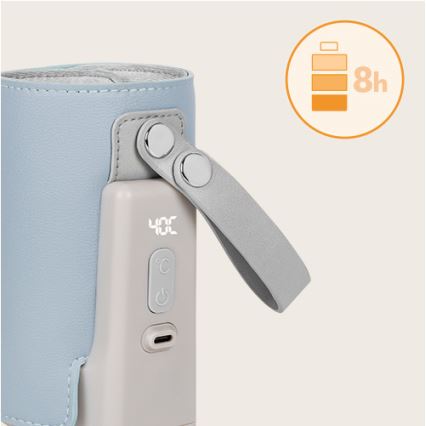 Prenositelný ohrievač fľašiek udržuje teplotu 40°C. Má šedý kryt, kožený remienok a displej s indikáciou teploty. Batéria vydrží 8 hodín.