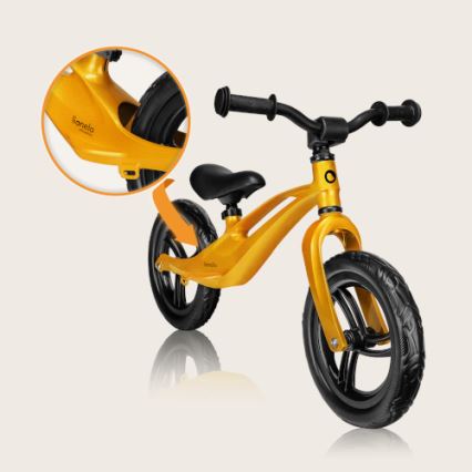 Zlatá odrážadlová kolobežka značky „Kanelo“ je zobrazená na svetlom pozadí. Má čierne sedadlo, riadidlá a kolesá. Zväčšený detail zobrazuje názov značky na ráme.