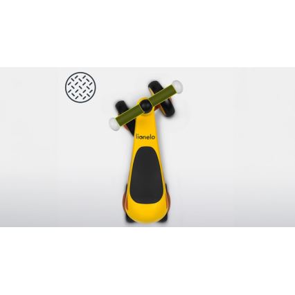 Žltý odrážadlo lionelo stojí na svetlom podklade. Je zobrazené zhora. Naľavo je malá ikona s vzorkou protišmykového povrchu.