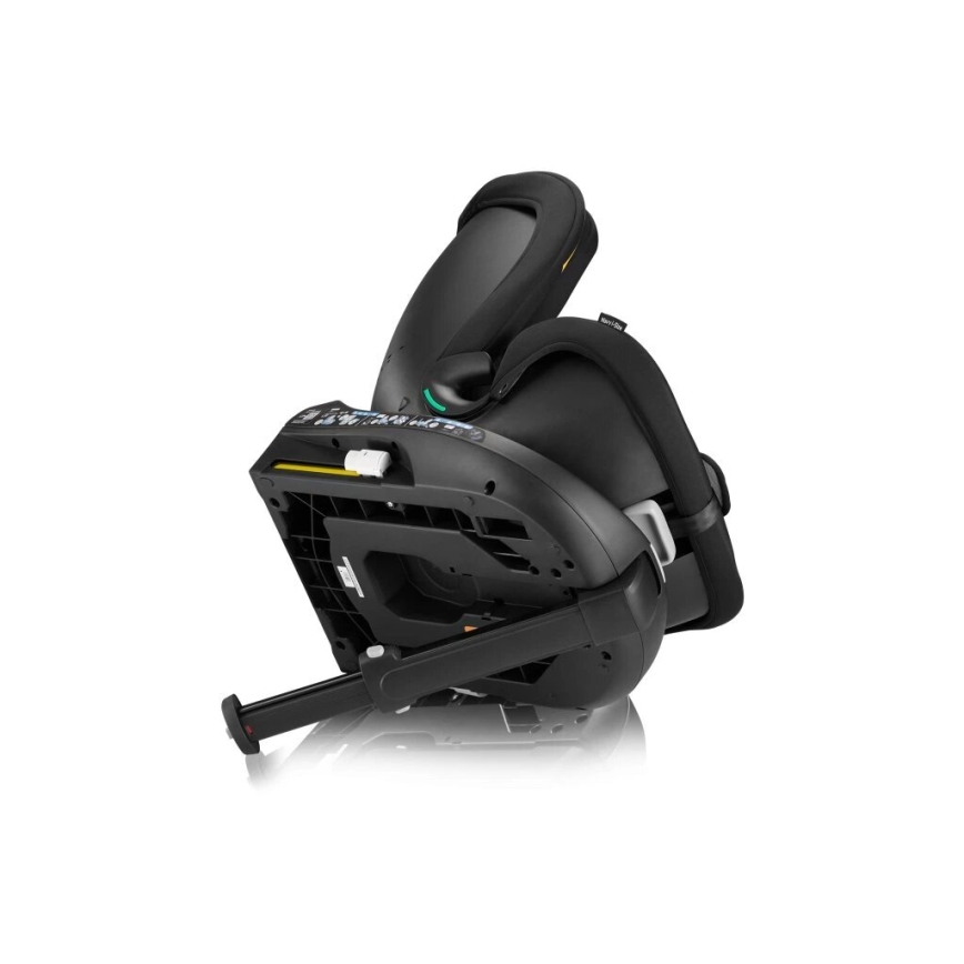 Autosedačka je naklonená dozadu, opierka je čiastočne zdvihnutá. Viditeľná je spodná časť s výsuvnou oporou. Je čierna s tmavosivými prvkami. Prostredie je biele pozadie.