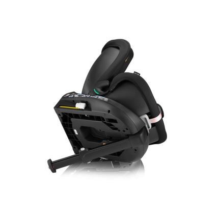 Autosedačka je naklonená dozadu, opierka je sklopená. Viditeľné sú jej detaily, ako opierka hlavy, pásy a mechanizmus na nastavenie sklonu. Nachádza sa na bielom pozadí.