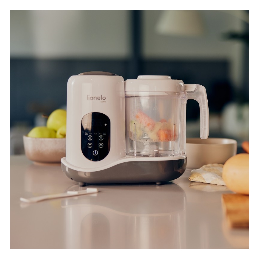 Mixér Lionelo Care pripravuje zeleninovú kašu. Nachádza sa na kuchynskej linke, vedľa misy s ovocím a vajíčkom.