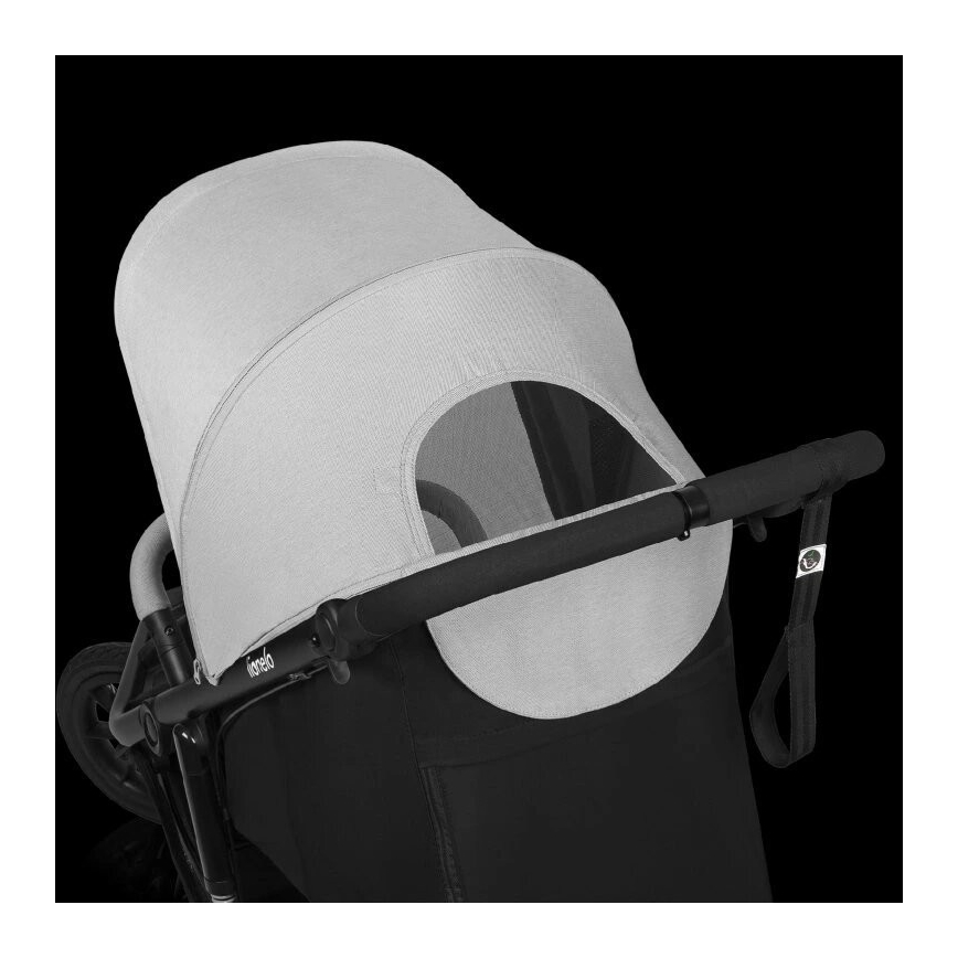 Športový kočík s šedou strieškou a čiernou konštrukciou. Strieška je čiastočne otvorená, odhaľujúc okienko. Kočík má čierne madlo. Na konštrukcii je viditeľné logo Joolz.