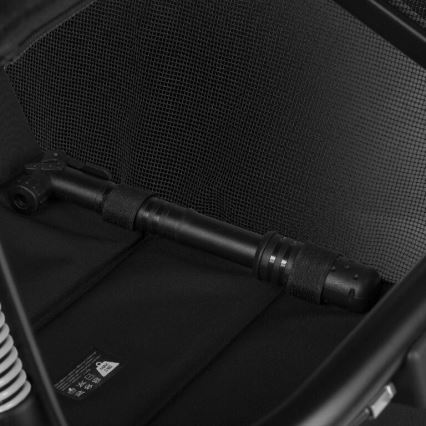 Čierna pumpa je uložená v čiernom textilnom vrecku s sieťovanou časťou. Pumpa je vodorovne umiestnená. Viditeľná je aj časť návodu s nečitateľným textom.