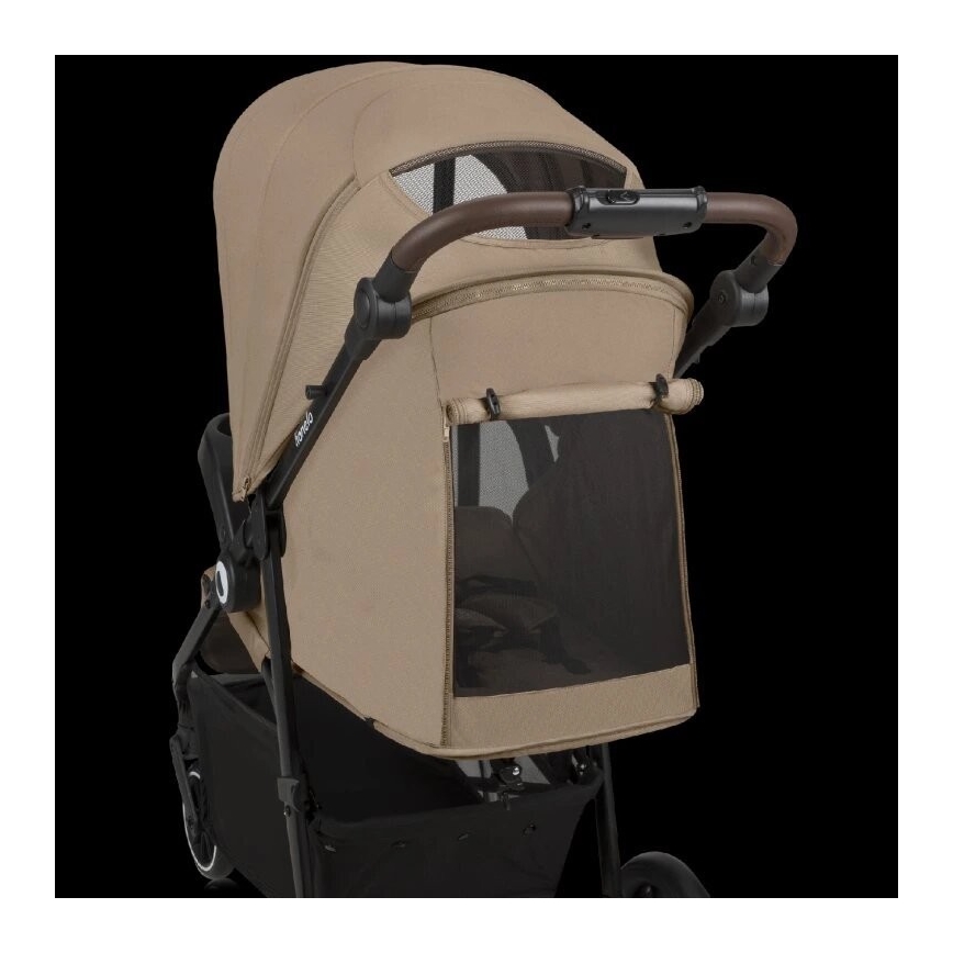 Kočík je zložený. Má béžovú striešku a čierne madlo. Bočné okno je sieťované. Kočík je na tmavom pozadí.