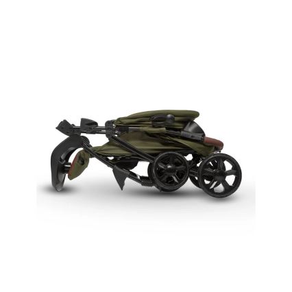 Detský kočík je zložený. Má olivovozelenú látku a čierny kovový rám. Je umiestnený na bielom pozadí.