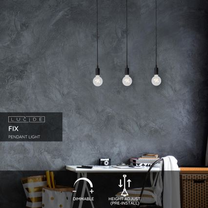 Tri závesné lampy svietia v miestnosti s tmavšou stenou. Lampy sú stmavené a výškovo nastaviteľné pred inštaláciou. Text: LUCIDE FIX PENDANT LIGHT, DIMMABLE, HEIGHT ADJUST (PRE-INSTALL).